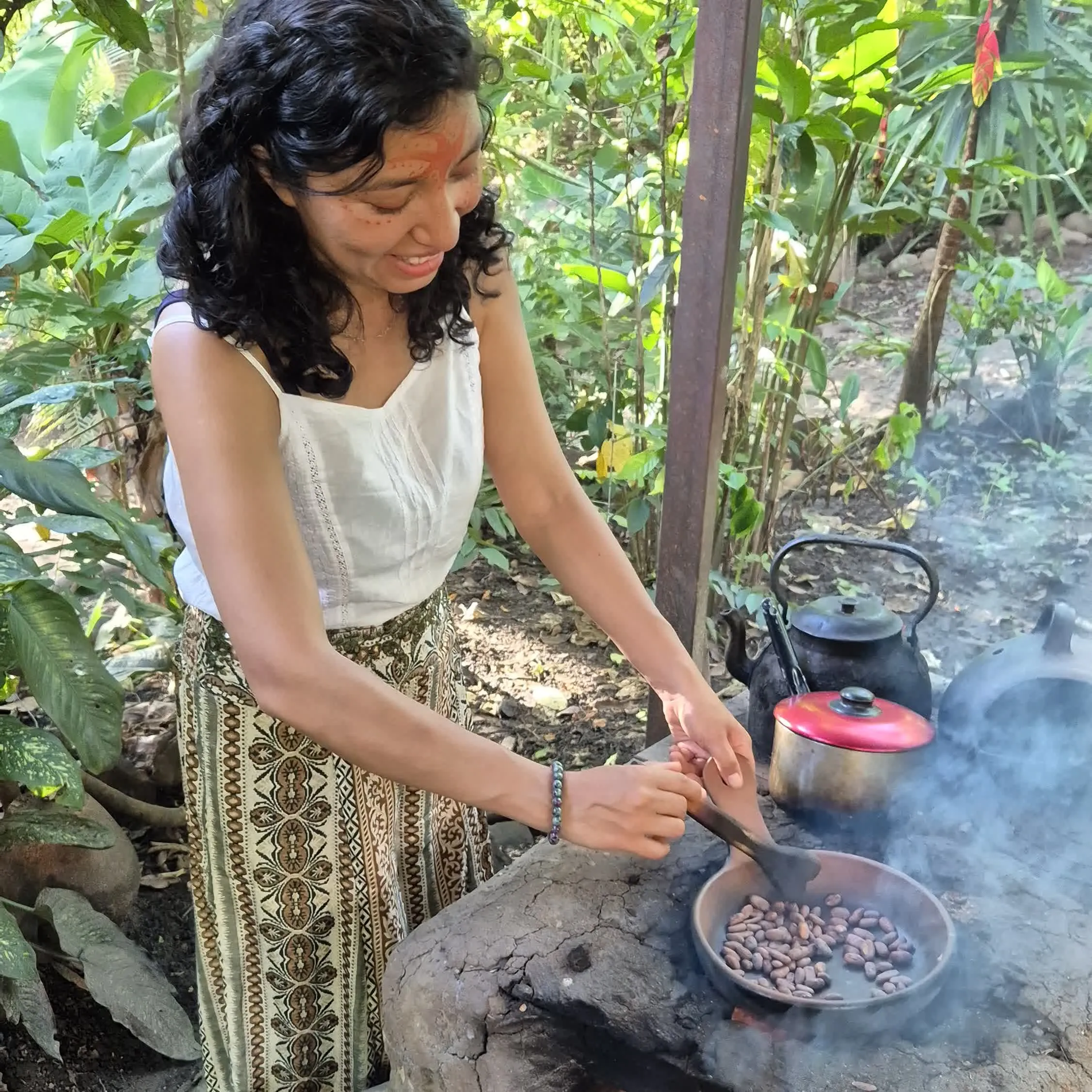 Mar roasting cacao beans over fire in the jungle