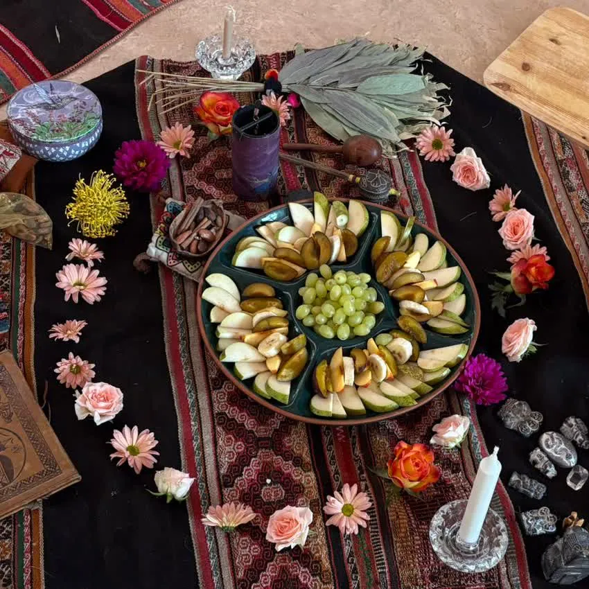 Ceremonial mesa with fruit offerings, flowers and candles on Andean textile